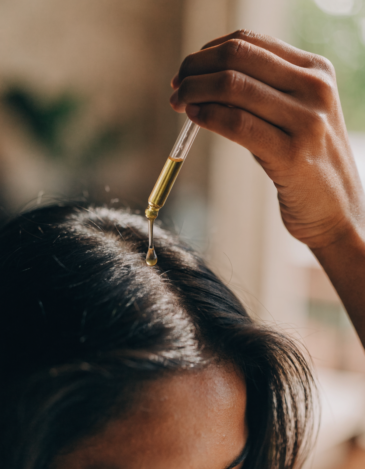 Applying a drop of batana oil to the scalp